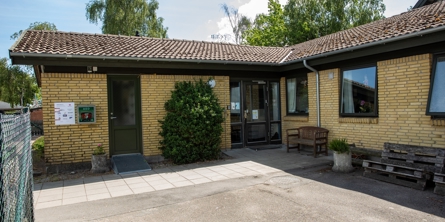 Indgangspartiet til daginstitutionen Stjernehøjen i Næstved Kommune. Bygningen er et vinkelhus i gule mursten. 