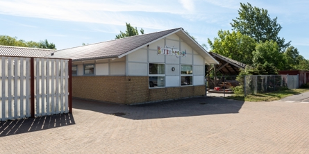 Indgangspartiet til daginstitutionen Birkehegnet i Næstved Kommune. Husets facader er en blanding af gule mursten og hvide plader. Der vokser træer bag bygningen.