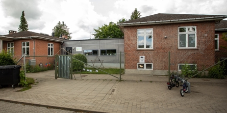 Indgangspartiet til daginstitutionen Møllen i Næstved Kommune. Institutionen består af to sammenbyggede etplans bungalow, opført i røde sten. 