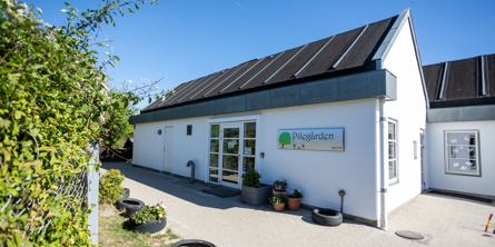 Indgangsdør til Pilegården, 2 bygninger som er sat sammen og begge bygninger er hvide med sort tag.