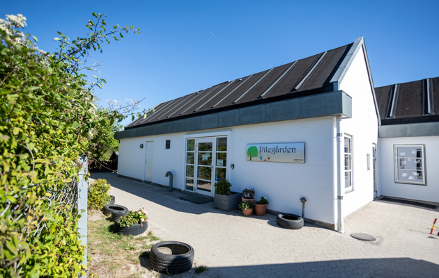 Indgangsdør til Pilegården, 2 bygninger som er sat sammen og begge bygninger er hvide med sort tag.
