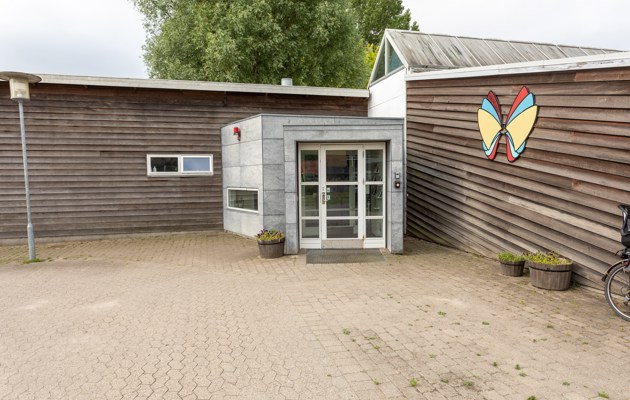 Indgangspartiet til daginstitutionen Sommerfugl i Næstved Kommune. Husets facader er i træ og indgangen er i metal og glas.