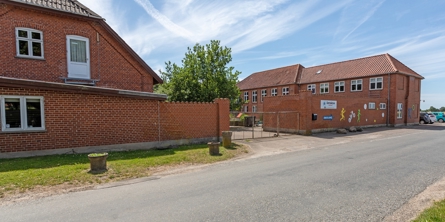 Indgangspartiet til daginstitutionen Kroppeloppen i Næstved Kommune. Huset er en ældre skolebygning, der ligger direkte ud til vej. 