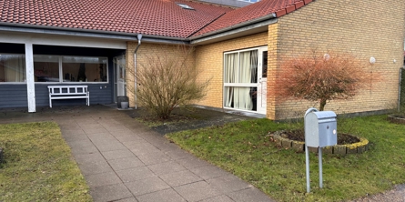 Indgang til Himmelhøj, Huset har gule mursten og rødt tag, der er også nogle vinduer og under det ene vindue er der en hvid bænk.