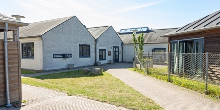 Indgangspartiet til daginstitutionen Grønebakken i Næstved Kommune. Bygningen består af flere sammenbyggede huse,  husene er i hvide sten. 